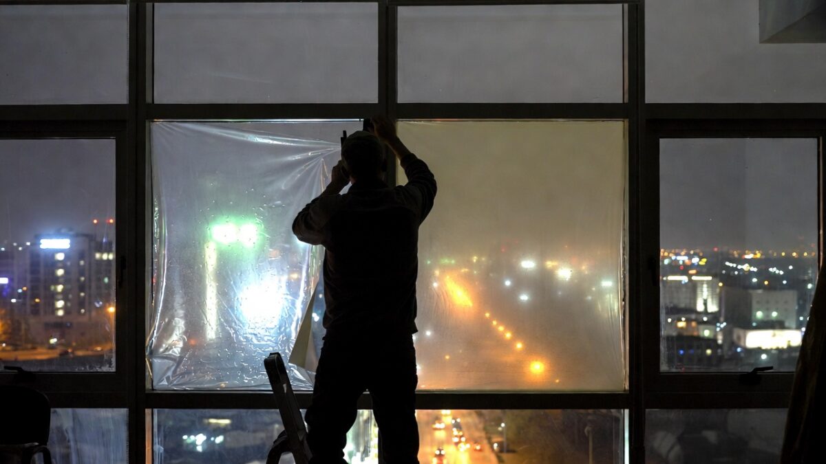 person installing window film at night image